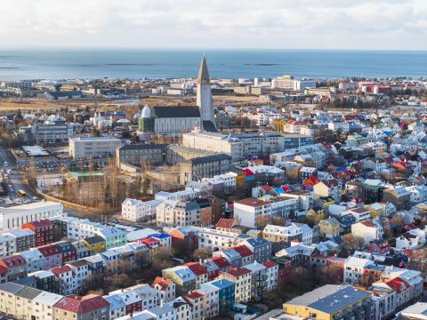 Loftmynd yfir miðborgina, Hallgrímskirkja áberandi fyrir miðri mynd. Háskólinn og sjór í fjarska. Hlutlaust veður, bjart.