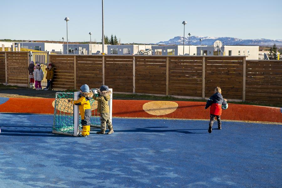 Children playing by a soccer goal on the Rauðhóll Preschool playground at the Ævintýri building 