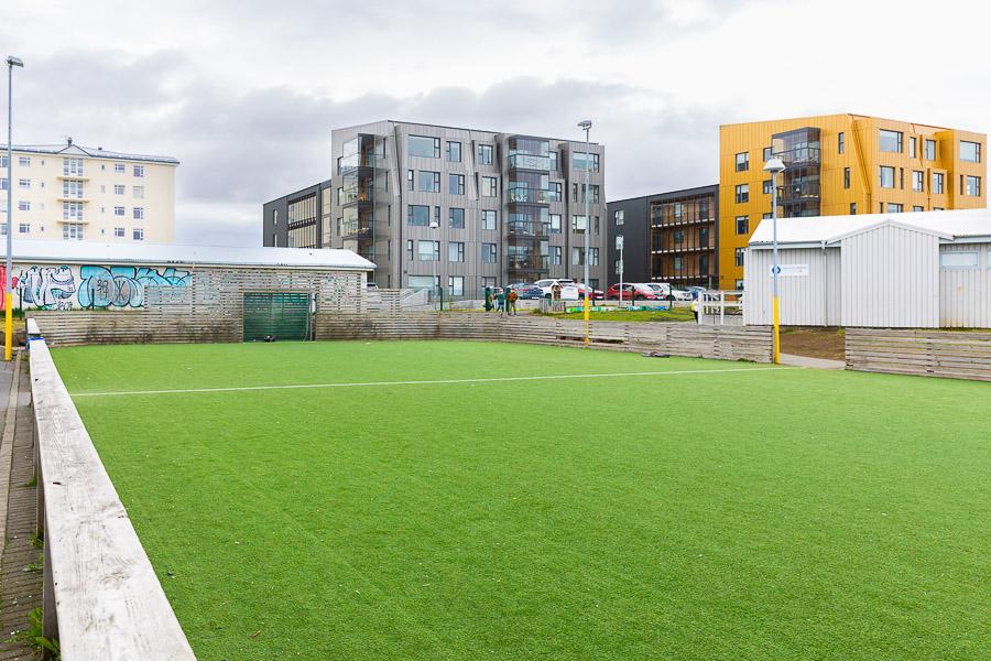 A soccer field with high-rise buildings in the background.