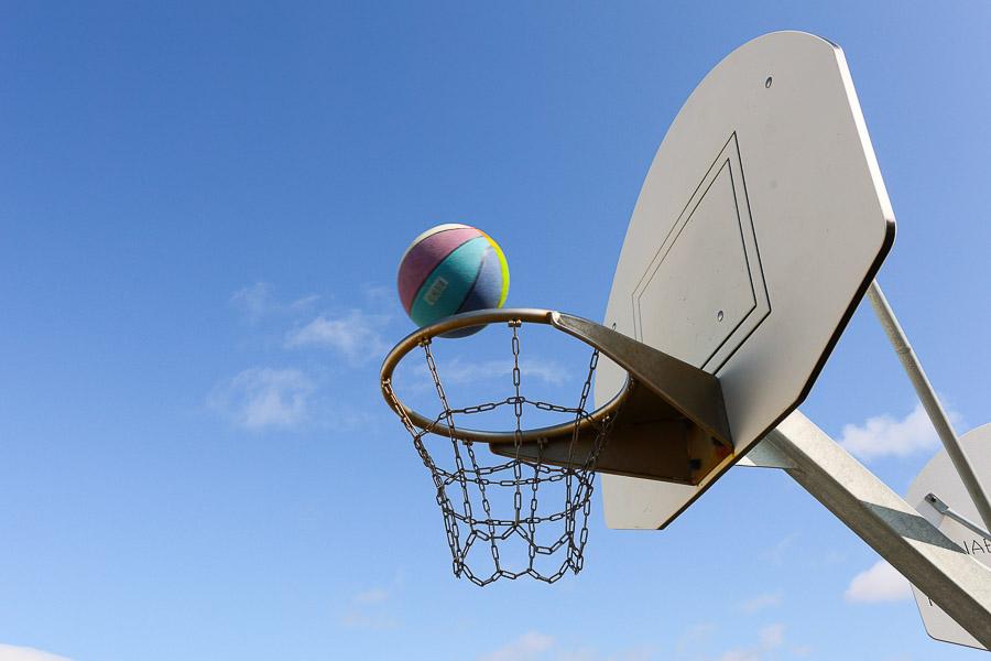 Basketball hoop and ball that's about to go into the basket.