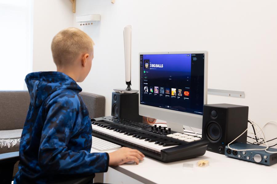 A child sits at a table with a screen, keyboard and other equipment. 