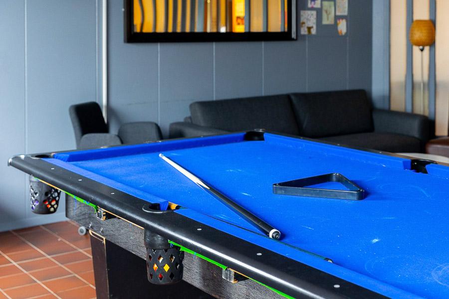 A blue pool table and a couch in the background. 