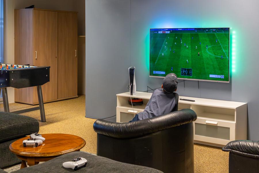 Child sitting in a black leather chair watching soccer on a screen. 
