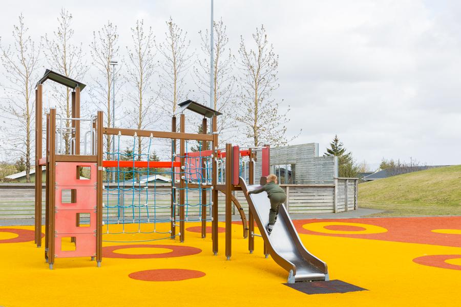 A yellow and red playground with a playground castle and a slide. 