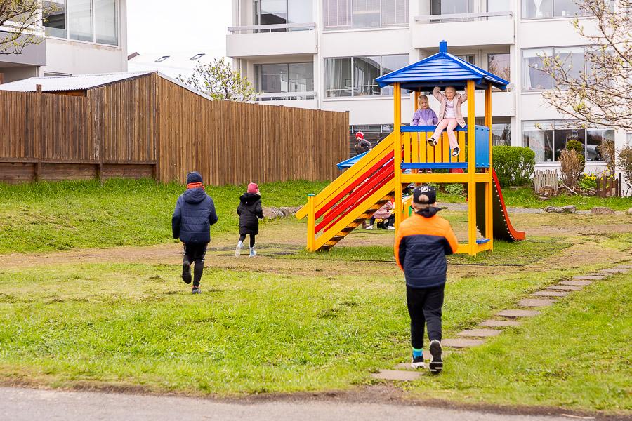 A slide with a tower on a grassy area. Children at play. 