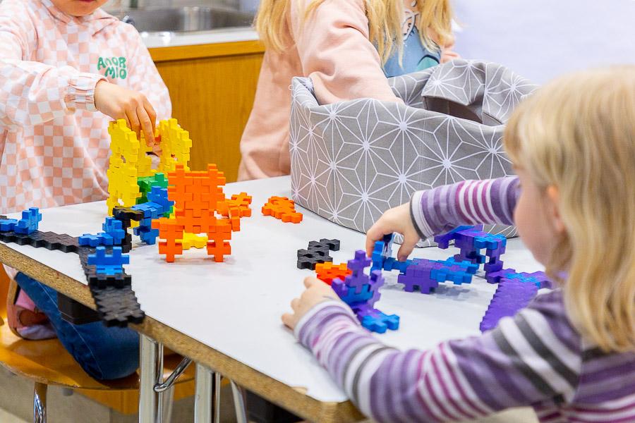 Children sit at a table building with blocks.