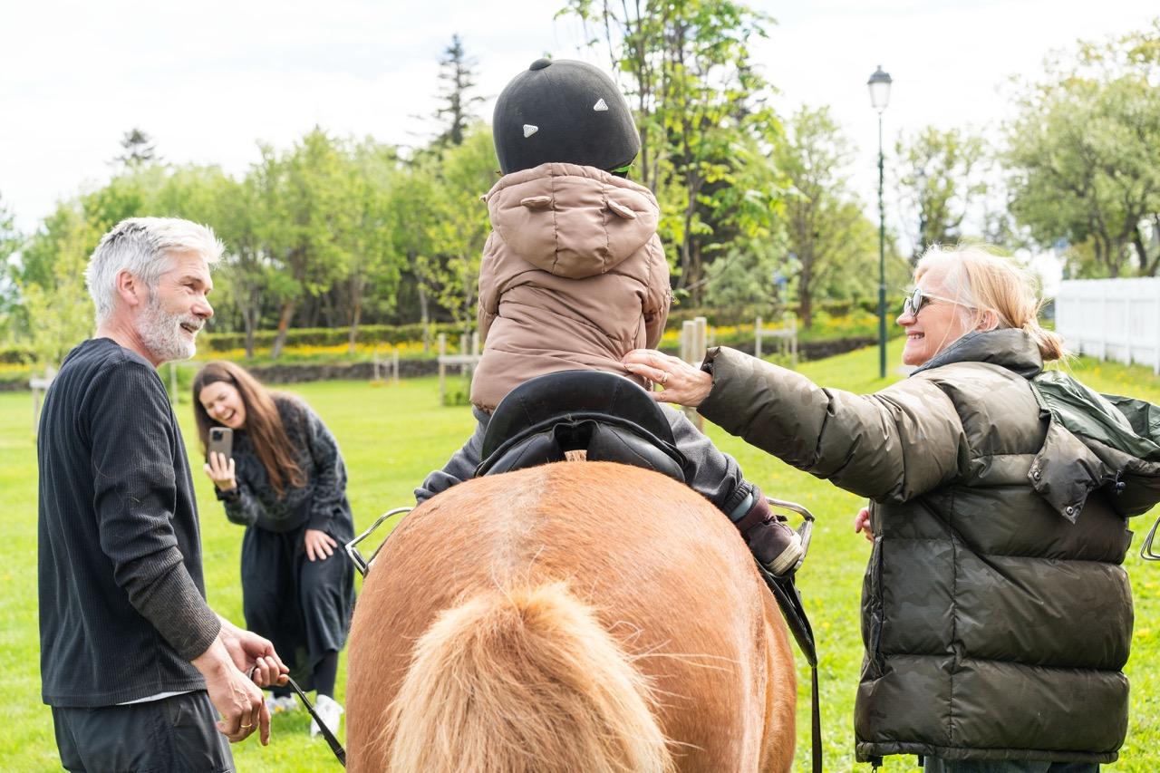 A child on horseback surrounded by adults.