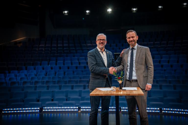 Eggert Benedikt Guðmundsson, formaður stjórnar Leikfélags Reykjavíkur og Einar Þorsteinsson borgarstjóri takast í hendur við undirritun samnings, á stóra sviði Borgarleikhússins.