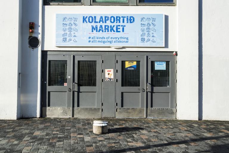 Hliðarinngangur í Kolaportið. Grá hurð, skilti fyrir ofan sem á stendur Kolaportið market