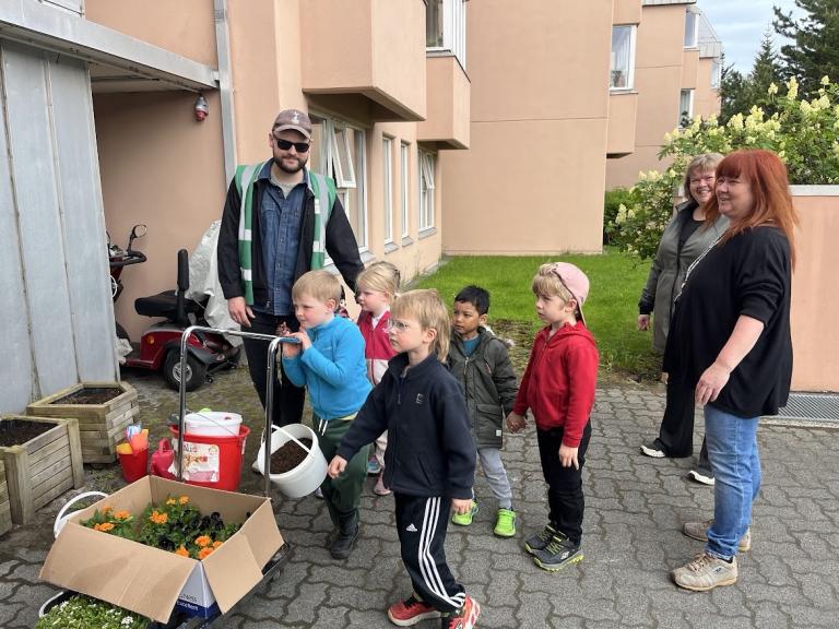 Hópur barna og fullorðinna standa við blómaker.